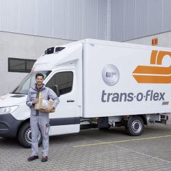 trans-o-flex Fahrer mit einem Paket in der hand vor dem Sprinter