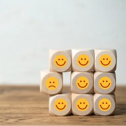 Viele Würfel mit lächelnden Smileys und einer der unzufrieden schaut